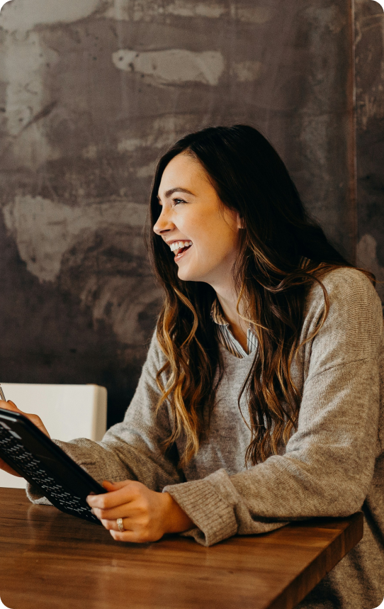Uma mulher de perfil sorrindo e segurando um tablet